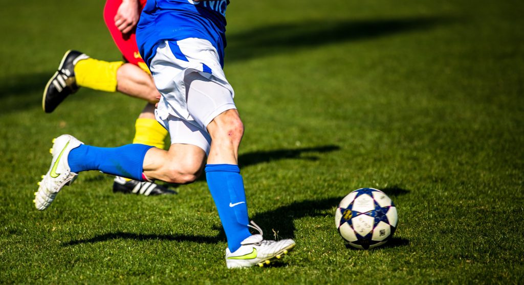 Två fotbollsspelare springer efter en fotboll