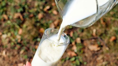 Ett glas komjölk hälls upp från en tillbringare.