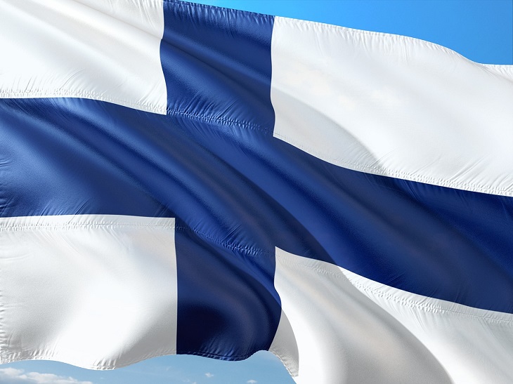 Finlands flagga blåser i vinden. Den är vit med ett blått kors.