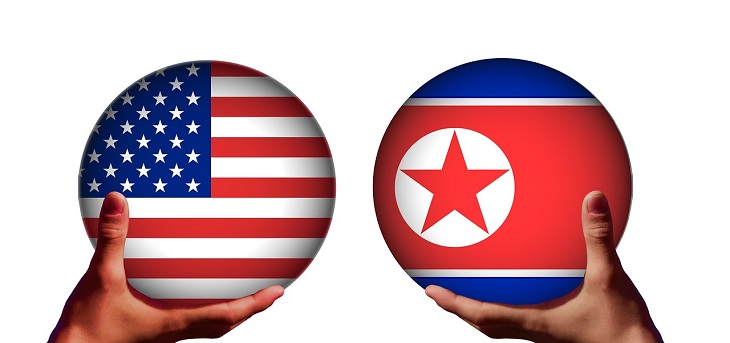 Två händer håller i varsin kula. Den ena kulan har USA:s flagga, med röda och vita ränder och vita stjärnor på en blå bakgrund i ena hörnet. Den andra kulan har Nordkoreas flagga. Den har en bred röd rand i mitten, blåa kanter och en vit cirkel med en röd stjärna i.