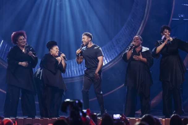 John Lundvik och hans gospelkör tar i och sjunger på scenen under Melodifestivalen.