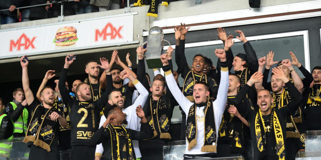 Bild på AIK:s lag som tillsammans höjer bucklan.