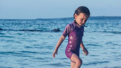 En flicka leker vid vattenbrynet.